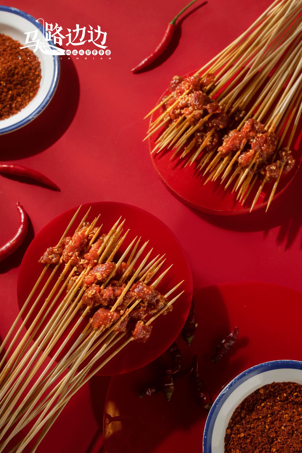 Chili-coated meat skewers on red plates at Ma Lu Bian Bian